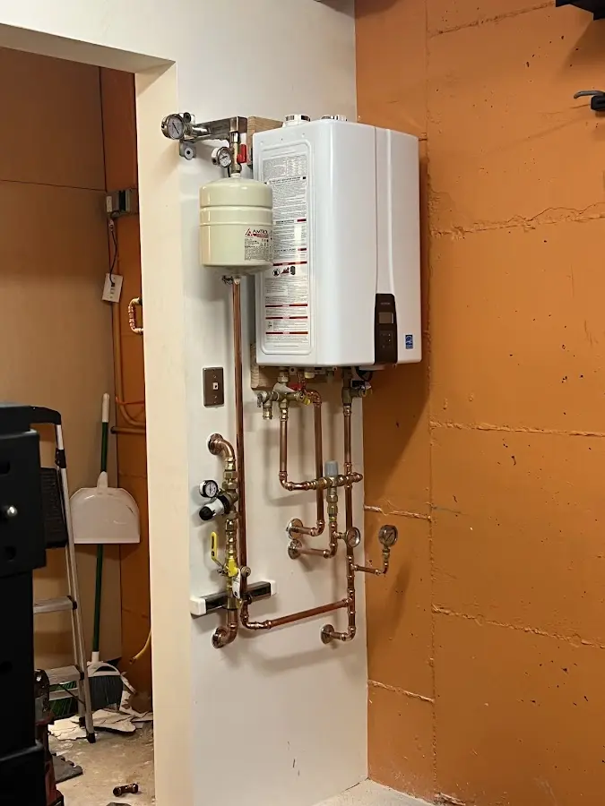 Plumbing technician inspecting water heater connections in Oswego
